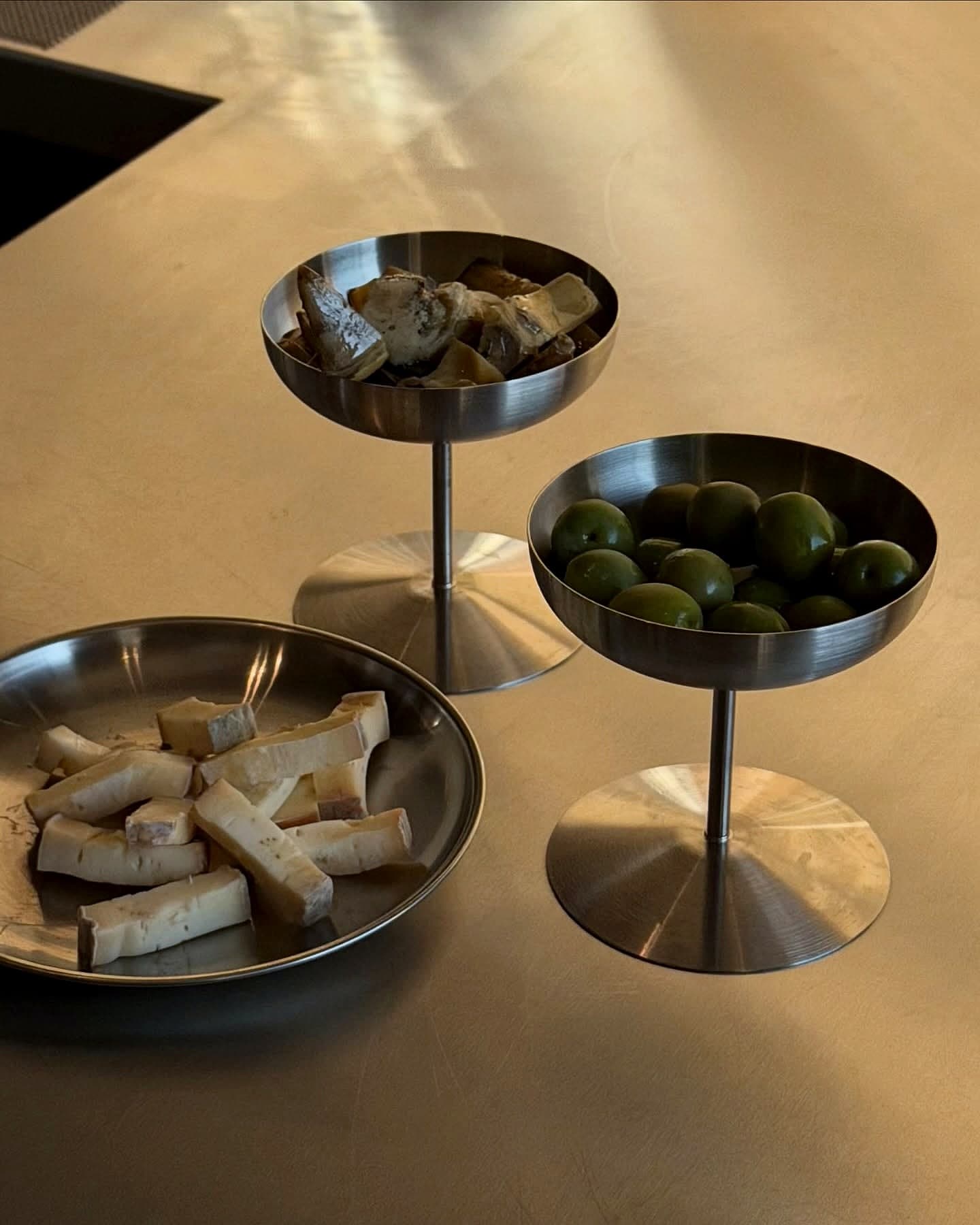 Snacks in steel coupes: olives, artichokes, cheeses